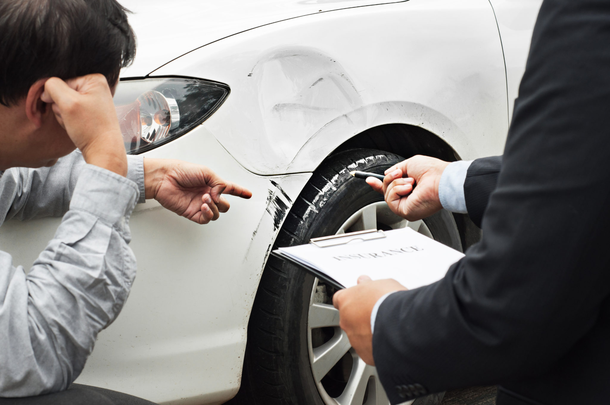 A man and an insurance agent examine car after an accident.