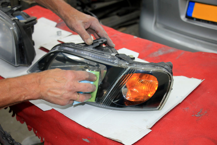 Man refurbishing a car headlight.