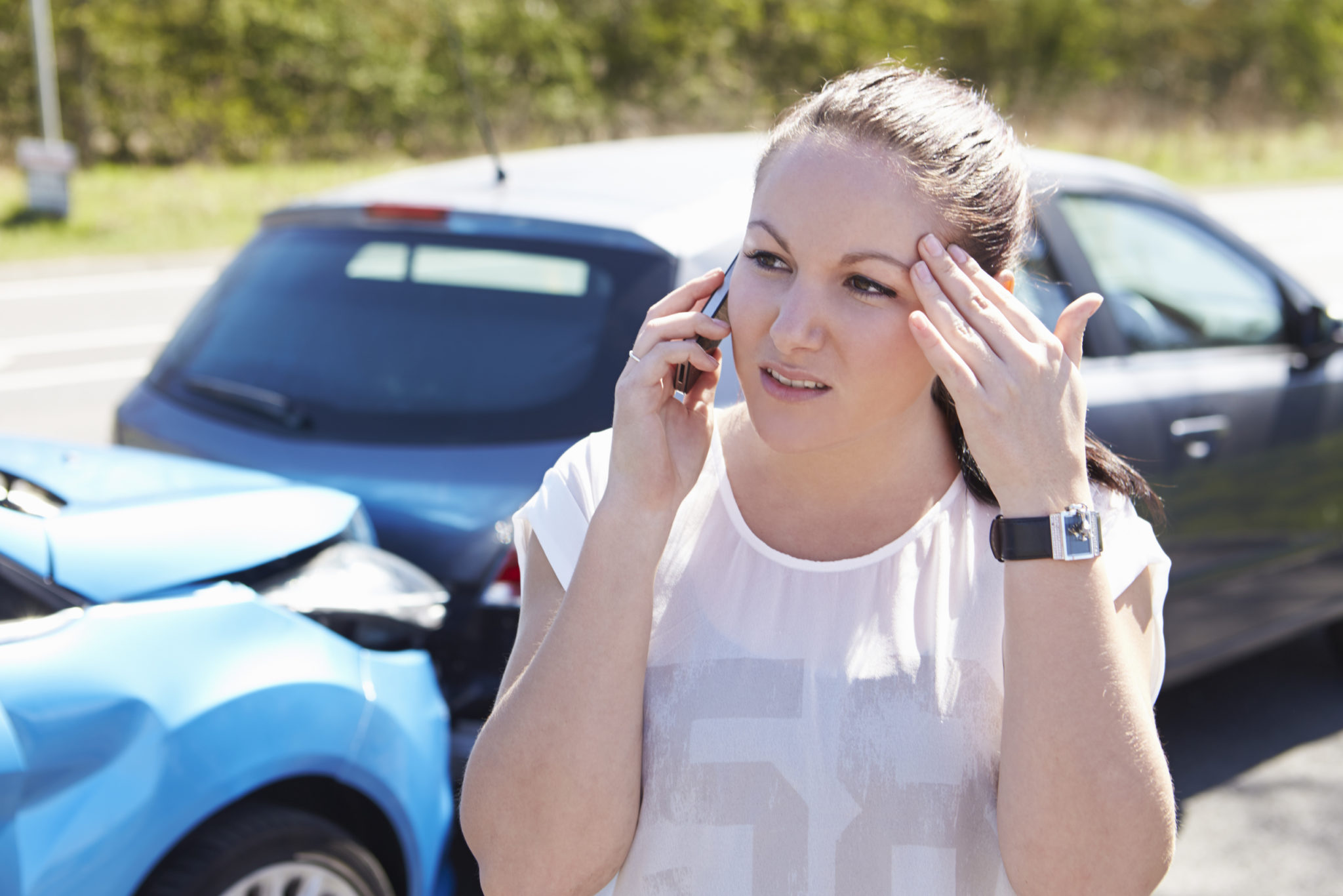 woman talks on her cellular phone next to a minor car accident scene